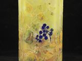 un gros plan d'un vase jaune orné de fleurs bleues
