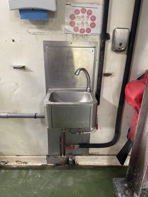 un lavabo dans un coin d'une pièce au sol vert
