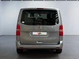 the back of a silver van parked in a white room