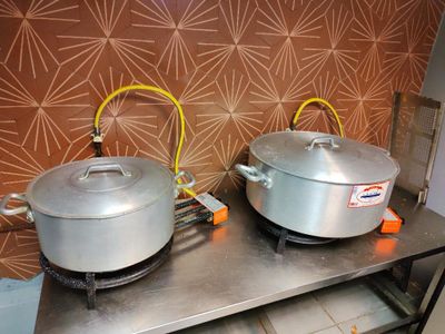 deux casseroles posées sur une table dans une cuisine, avec un mur derrière elles