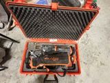 une mallette orange posée par terre, contenant des outils