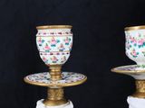 two white and gold candlesticks with floral designs on them