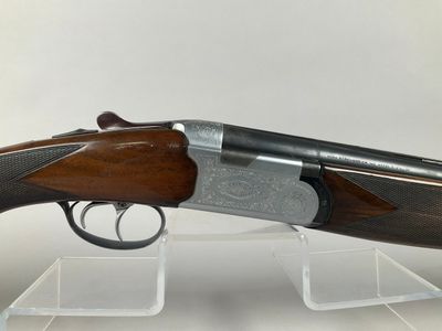 a shotgun with a wooden barrel and a metal handle on a clear stand