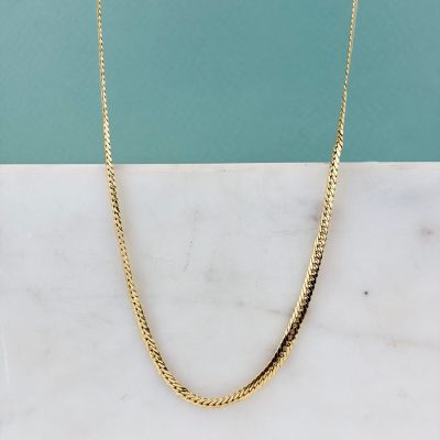 a close up of a gold necklace on a marble surface