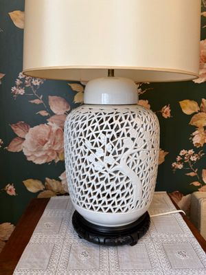une lampe posée sur une table devant un papier peint à motifs floraux