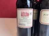 two bottles of red wine sitting on top of a white table