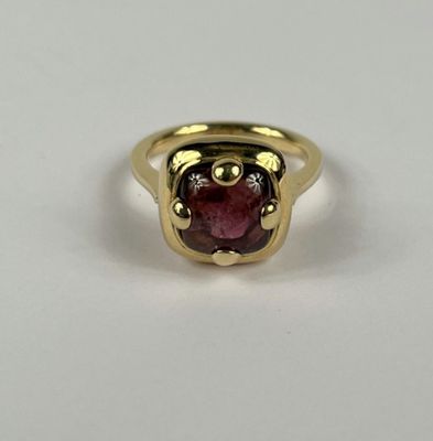 gros plan d'une bague en or avec une pierre rouge