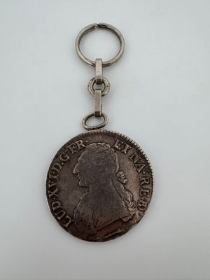 un gros plan d'une pièce de monnaie accrochée à un porte-clés posée sur une surface blanche