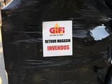 une pile de sacs poubelles noirs sur laquelle est accrochée une pancarte