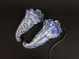 une paire de chaussures en porcelaine bleue et blanche posées sur un fond noir