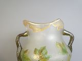 un vase blanc orné de feuilles vertes, posé sur une table