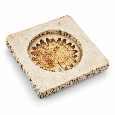 square stone coaster with a flower design on it