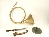 a brass horn, a knife, and other items on a white surface