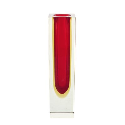 un vase rouge bordé d'or posé sur une surface blanche