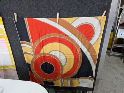 une table et une chaise dans une pièce où est accrochée une tapisserie au mur