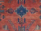 an antique rug with a blue and red design on a red ground