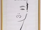 chanel, a portrait of a woman ' s face in black and white, hangs on a wall