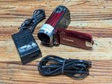 a red camera sitting on a wooden table with a charger