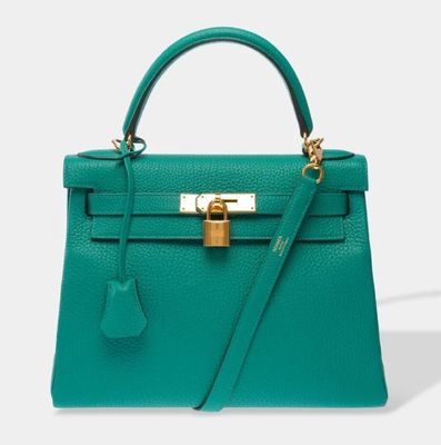 a green leather handbag with a gold lock on the handle