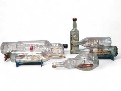 three bottles with a ship inside of them on a white surface