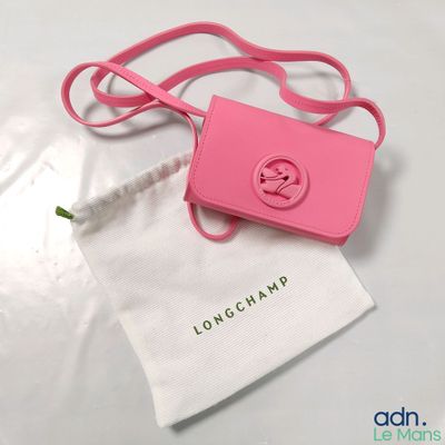 un petit sac rose muni d'une anse rose, posé sur une table blanche