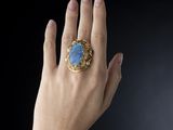 someone is holding a ring with a blue stone in it