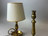 une paire de bougeoirs en laiton et une lampe posés sur une table blanche