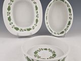 two white and green dishes with green leaves on them on a table