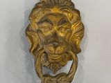 poignée de porte en forme de tête de lion en laiton sur un mur blanc