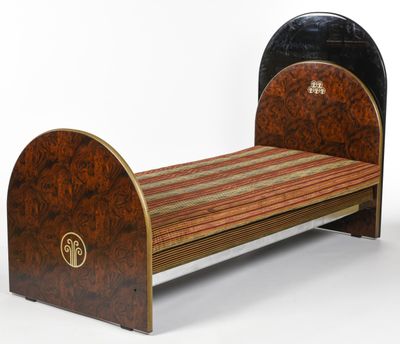 un petit lit avec un cadre en bois et un couvre-lit rayé