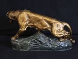 bronze statue of a lion on a rock on a black background