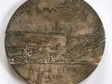 une médaille d'argent sur laquelle est représentée une ville