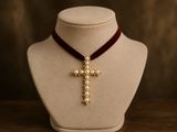 a close up of a necklace with a cross on a mannequin