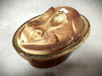 un bol marron orné d'un visage, posé sur une table
