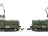 two green trains sitting side by side on a white surface