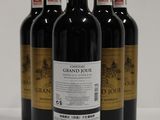 four bottles of red wine are lined up on a white surface