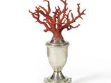 un vase en argent contenant un corail rouge, posé sur un fond blanc