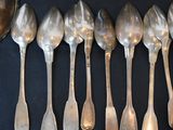 six silver spoons are lined up in a row on a black surface