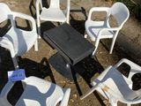 several white plastic chairs and a table in a circle on the ground