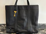 un sac fourre-tout en cuir noir orné d'une clé dorée sur la poignée