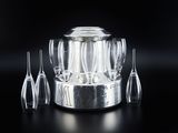 four wine glasses and a silver wine cooler on a black table