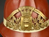 a red fireman ' s helmet with a gold emblem on it