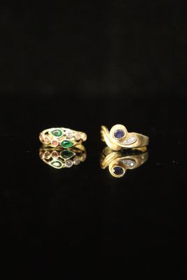 a pair of gold rings with emeralds and sapphires on a black surface