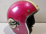 un casque de moto rose, orné d'un autocollant, posé sur une table