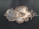 a silver plate with a picture on it on a black surface