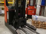 a forklift in a warehouse with pallets in the background