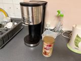 a coffee maker sitting on a kitchen counter next to a cup of coffee
