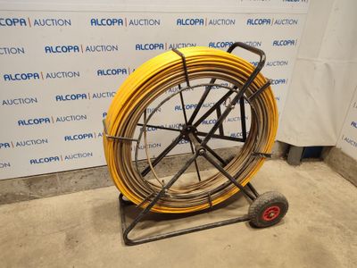 a yellow hose on a cart in front of a wall