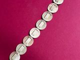 a close up of a silver bracelet on a pink background