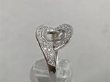 a close up of a heart shaped diamond ring on top of a glass bottle